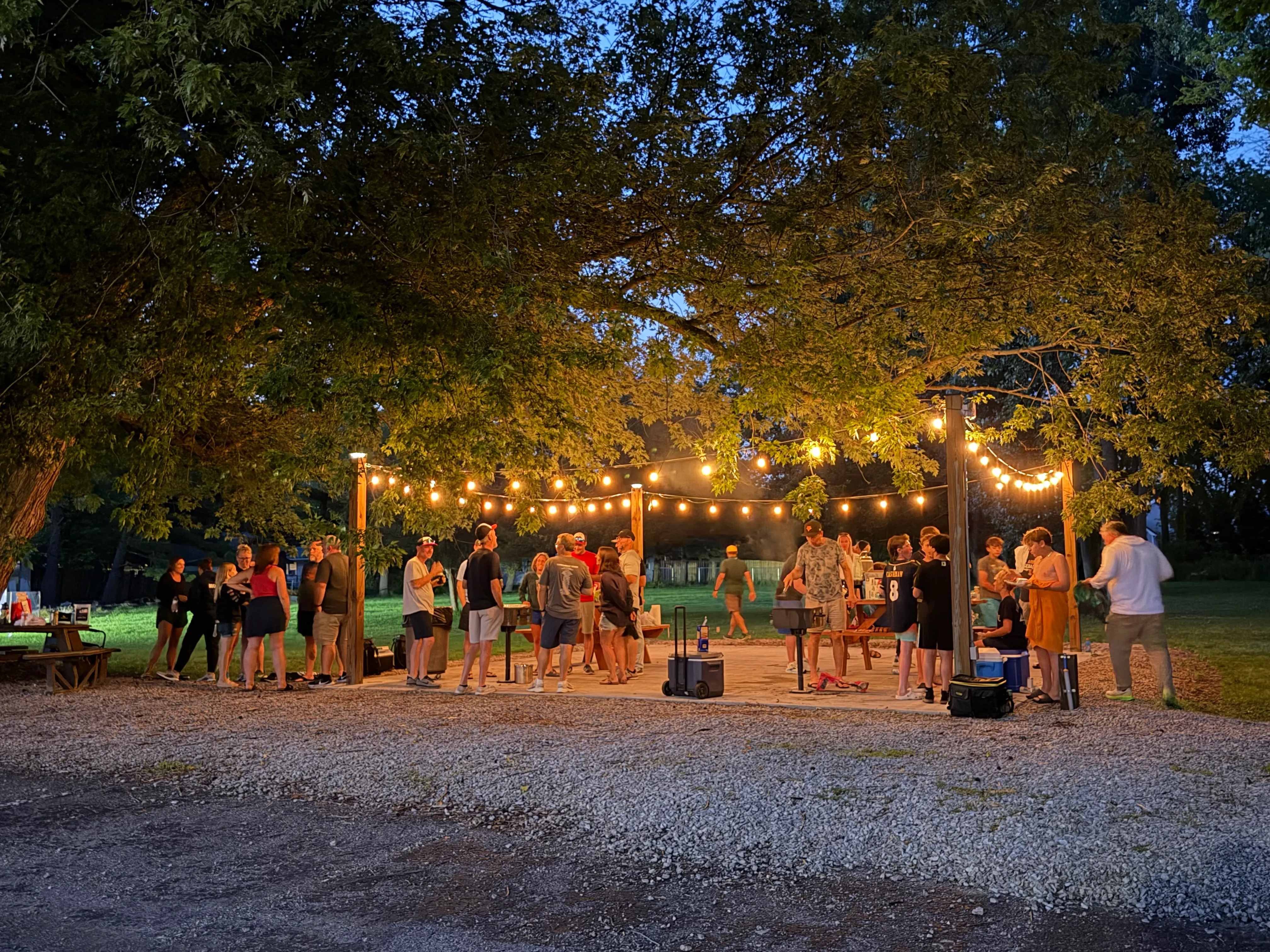 Group enjoying the BBQ patio with string lights on a summer evening